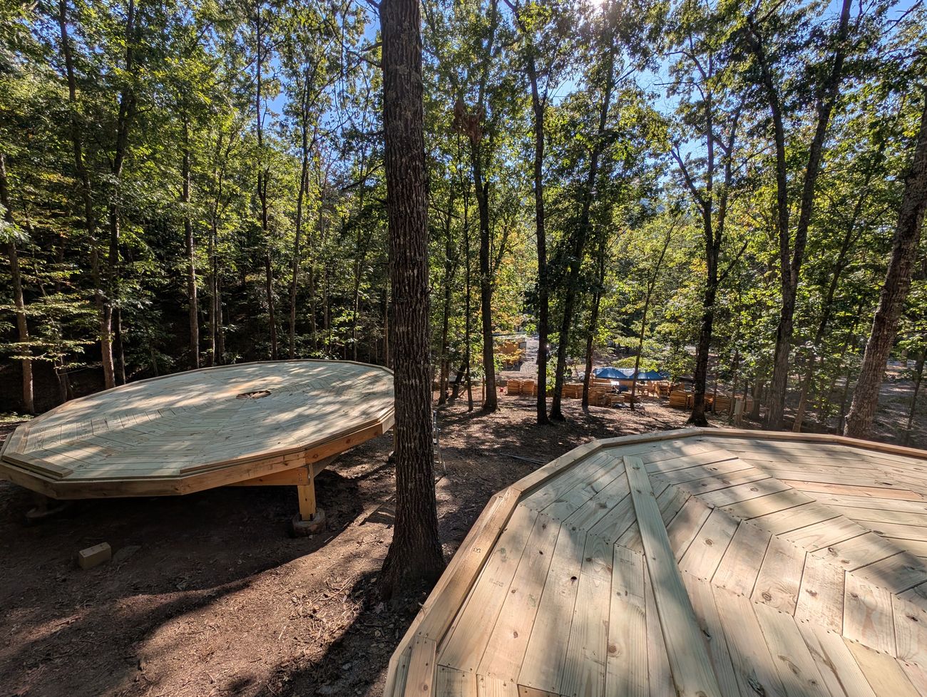 Two completed octagonal dome cabin decks among the trees