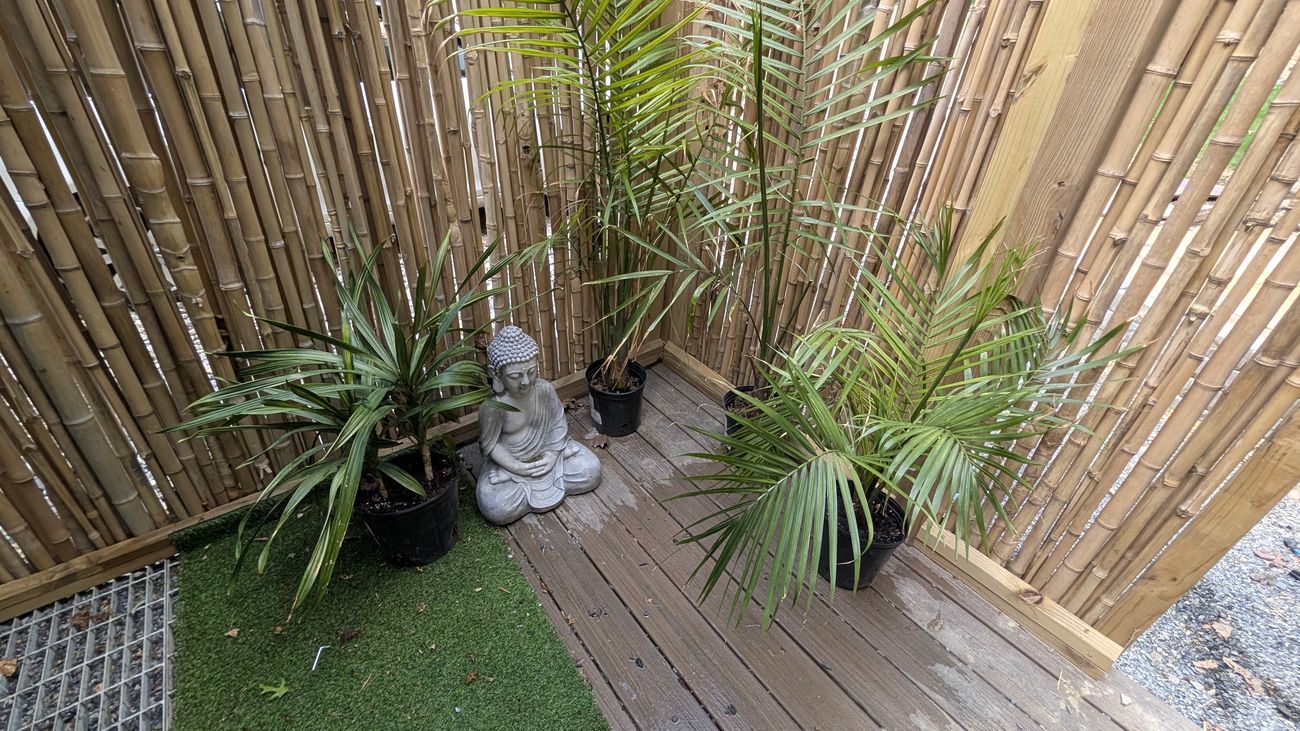 The bamboo outdoor shower with a Buddha statue and palms